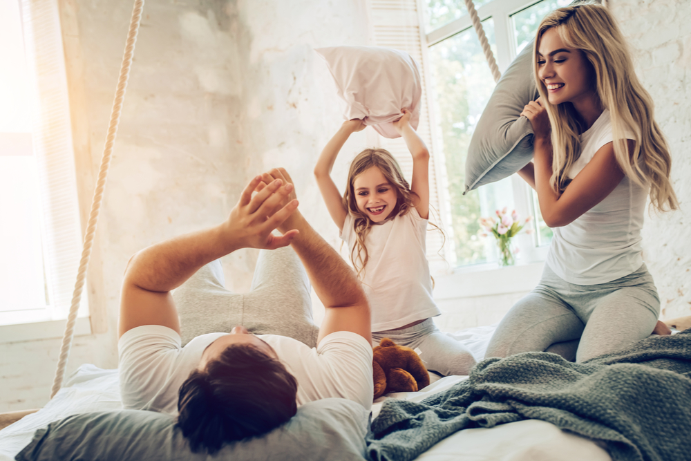 Family having a pillow fight on America's best oversized mattress: The Family Bed by Taylor & Wells.